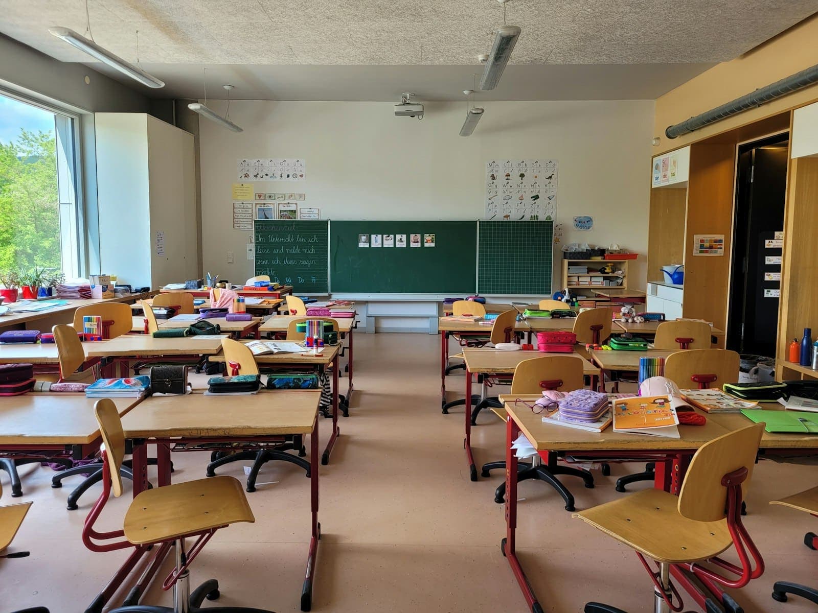 Sala de aula com carteiras, cadeiras e material escolar
