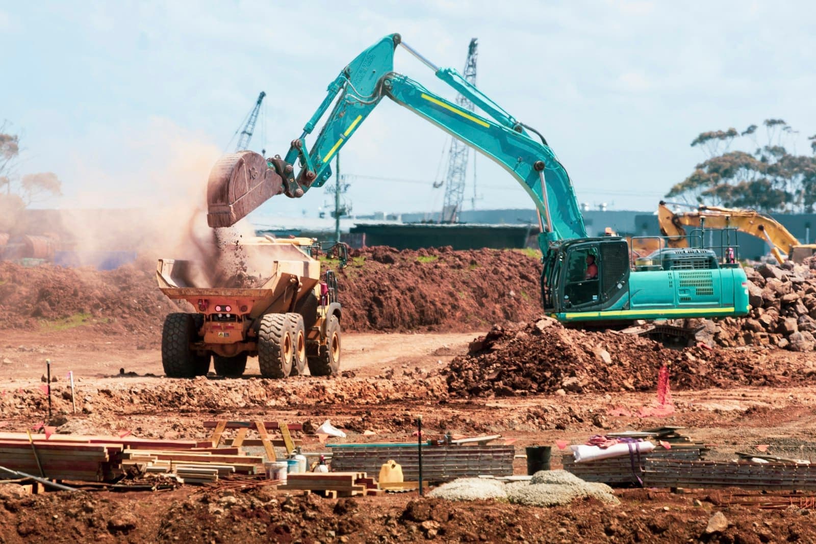 Escavadeira despejando terra em um caminhão basculante em uma obra